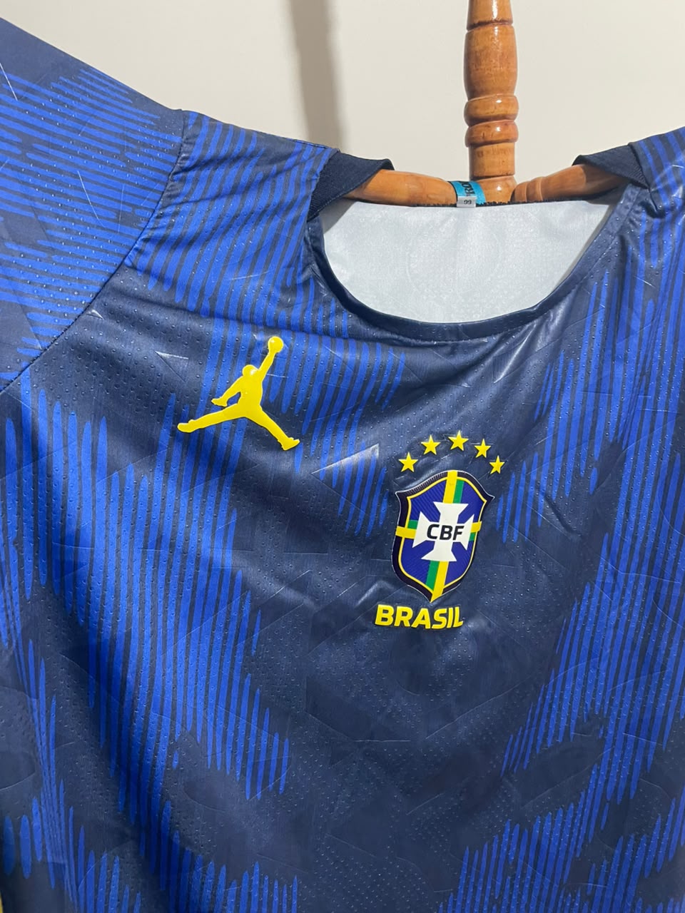 Modelo azul da camiseta Brasil 2026 com brasão frontal